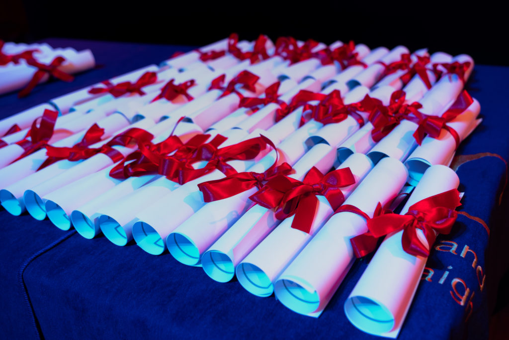 Scrolls with red ribbons binding them on a table with a blue table cloth. This photo was taken at one of the Silver Award Ceremonies. 