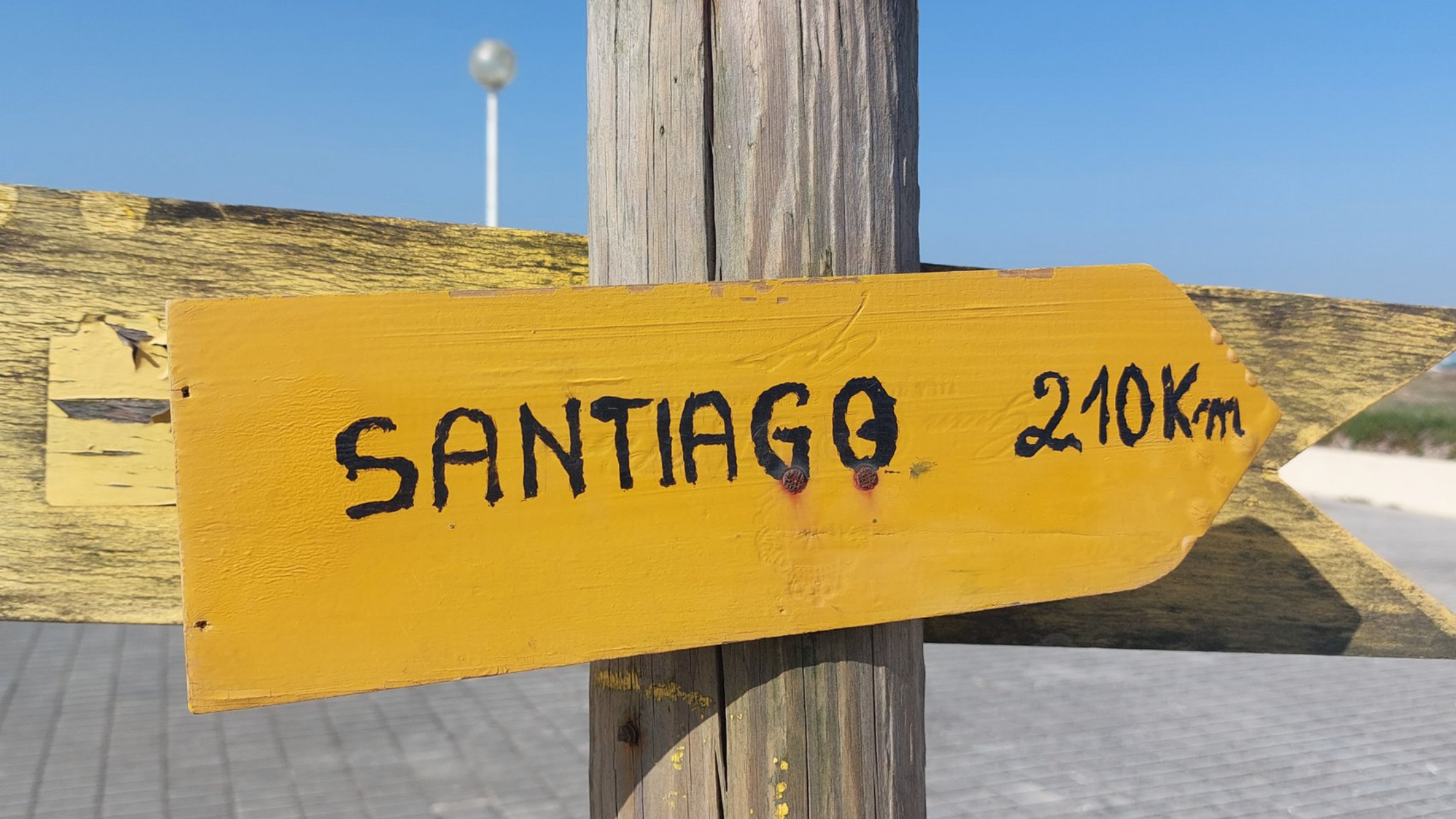 Wooden sign pointing to the right with the text "Santiago 210km".