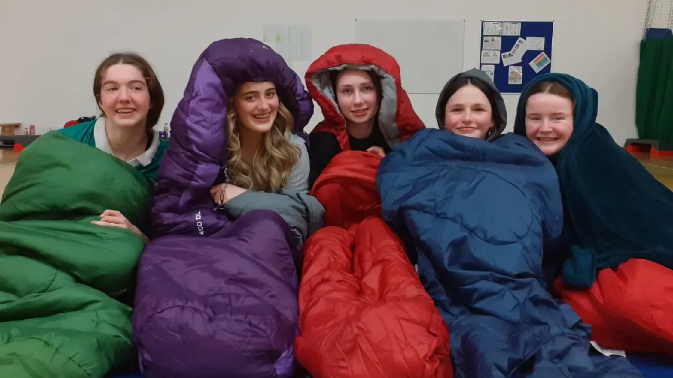 Five students in their sleeping bags in the school.